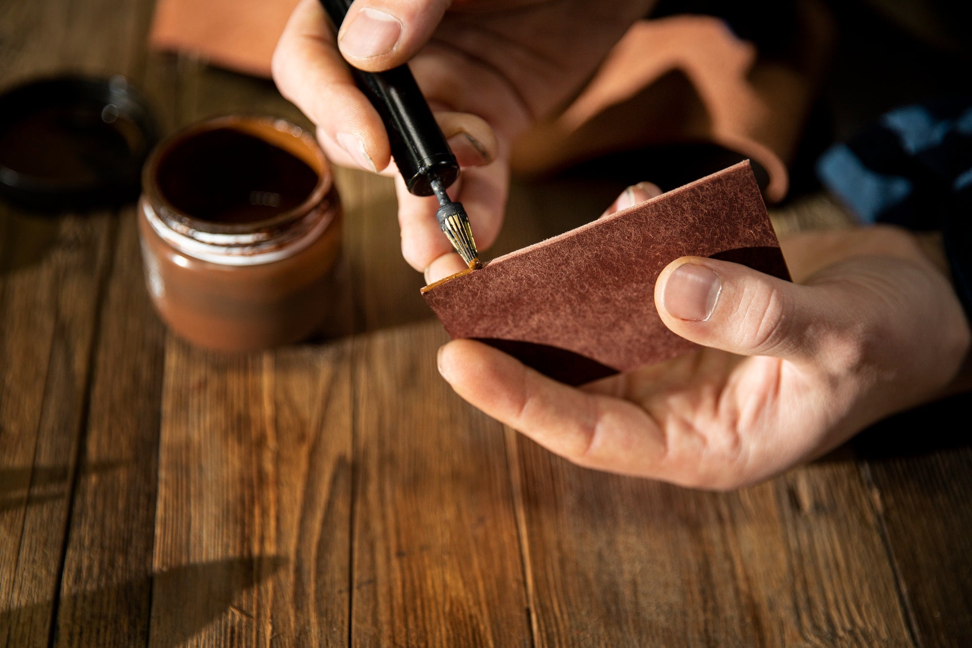 Person applying a substance to a Brenid Phone Case Leather with a small brush.